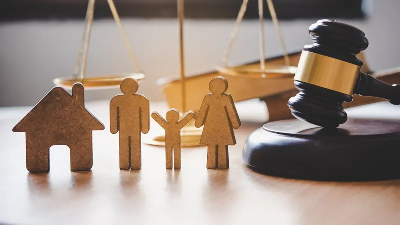 Ahşap ev ve aile figürleri yanında hakim tokmağı ve adalet terazisi